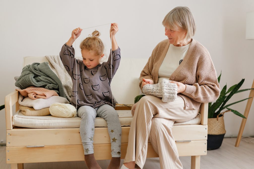 Grandmother sitting with her granddaughter, knitting together
