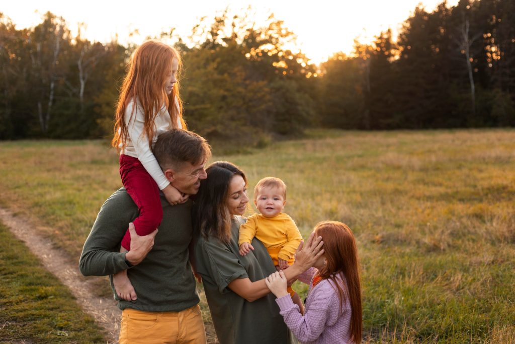 Family of five with three children smiling together outdoors at sunset