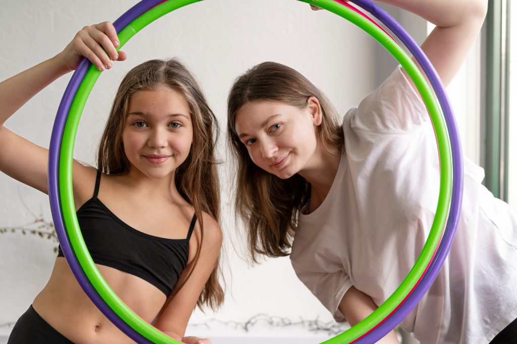 Mother and daughter smiling together while looking through a hula hoop